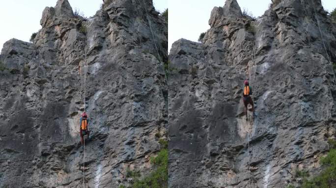 男性攀登者爬到攀岩岩石上的时间间隔。他戴着红色安全帽，背着黄色背包。