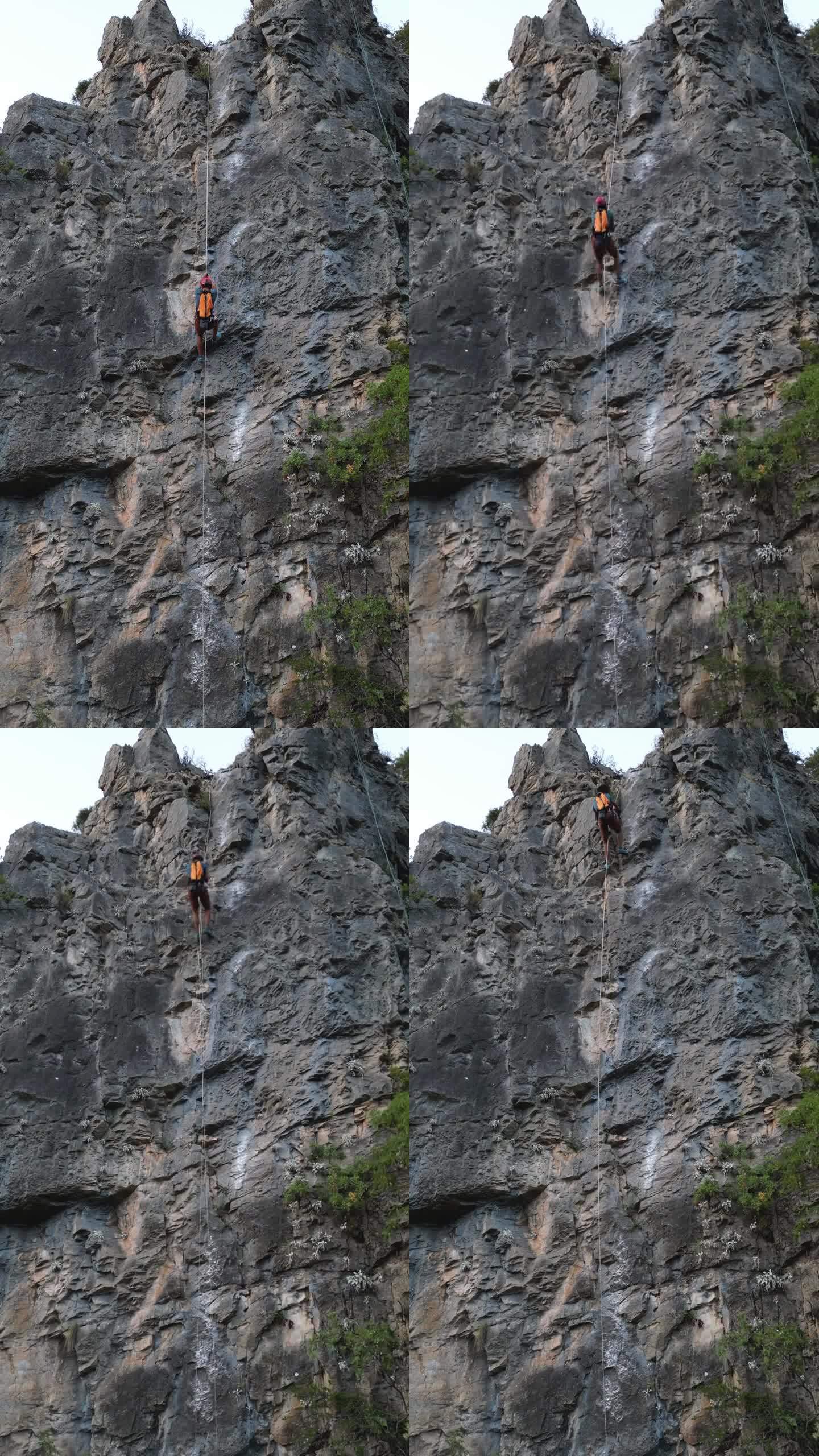 男性攀登者爬到攀岩岩石上的时间间隔。他戴着红色安全帽，背着黄色背包。