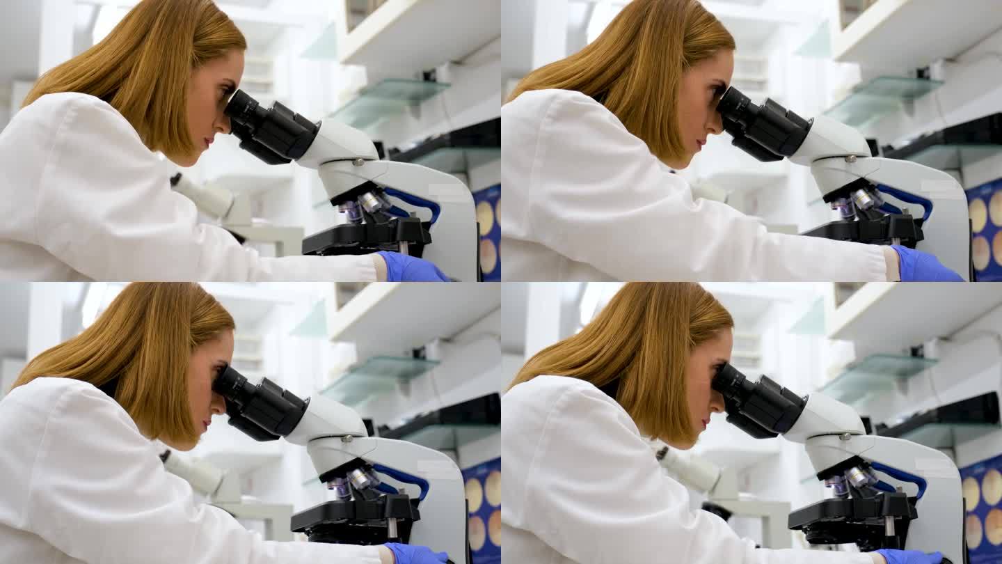 女科学家在生化实验室通过显微镜观察。