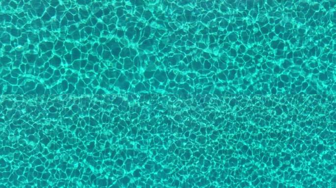 地中海的蓝绿色海水，底部有沙。空中俯瞰透明的蓝色海水与太阳光线的反射