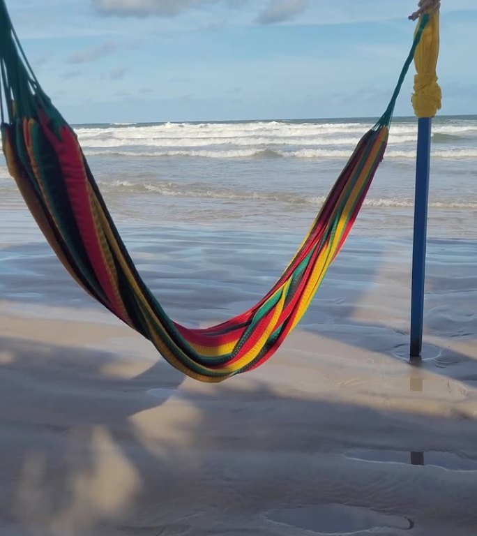 吊床悬挂在沙滩上，背景是平静的大海