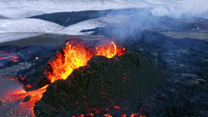 由电影级4K无人机拍摄的航拍画面展示了冰岛一座喷发的火山，快速流动的熔岩和冬日的背景。