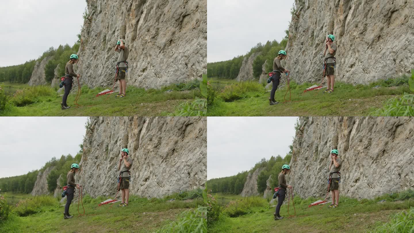 一对夫妇在岩石底部穿上攀岩装备