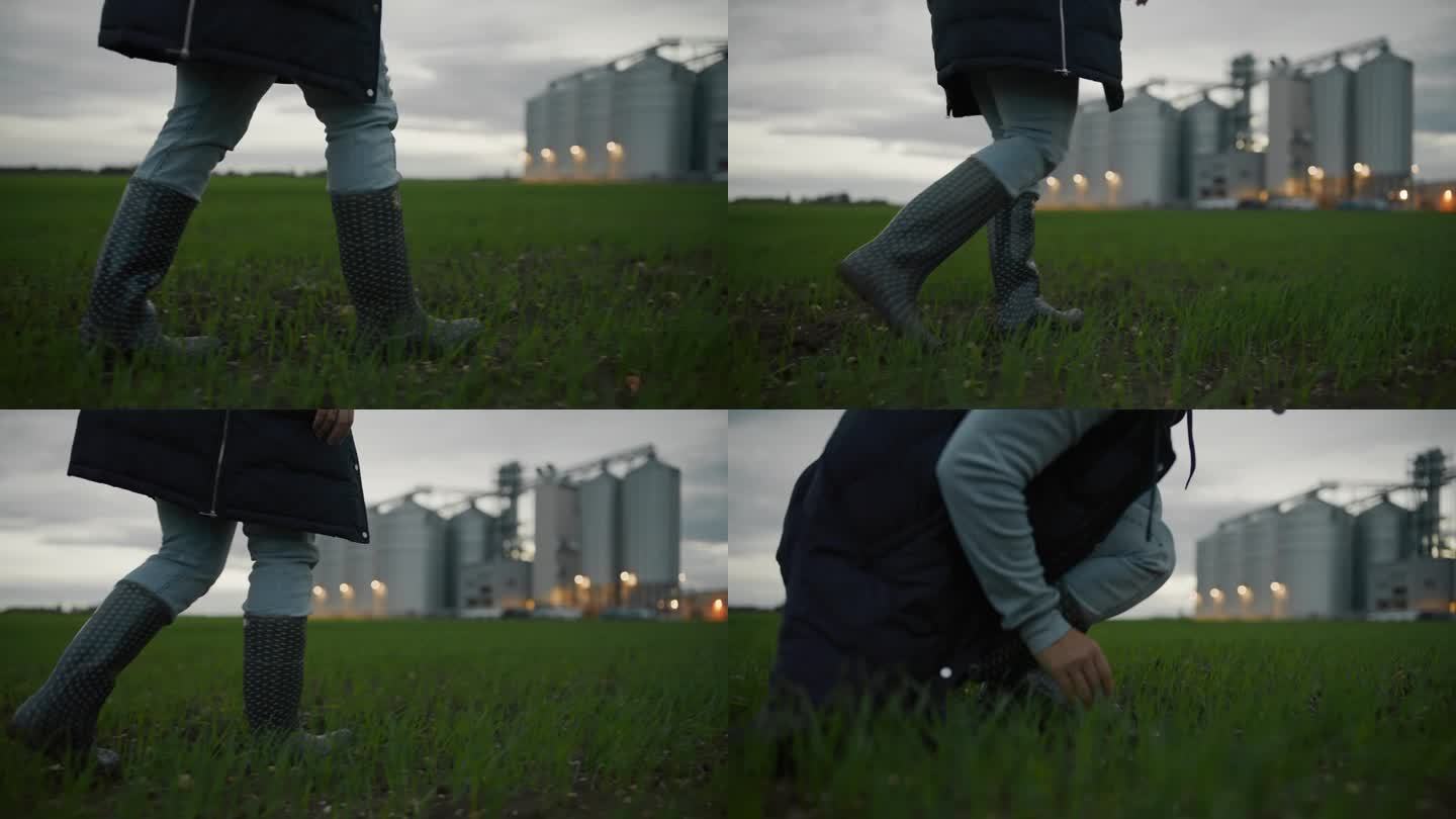跟踪拍摄一个穿着橡胶靴的女人在农场的筒仓附近行走