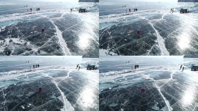 航拍的女孩在贝加尔湖冰封的蓝色透明冰面上滑冰，冰面上有裂缝。自然地标。冬天的风景。热门旅游目的地。