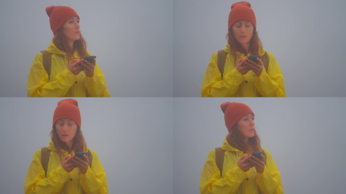 森林定向运动。背着背包的女游客在大雾中徒步旅行时迷路了，她用智能手机地图寻找正确的路