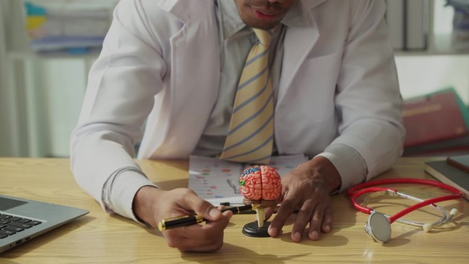 男医生谈论医生诊断黑人男子脑模型或疾病结果描述一个程序或医疗保健专业医生在办公室治疗或讨论手术