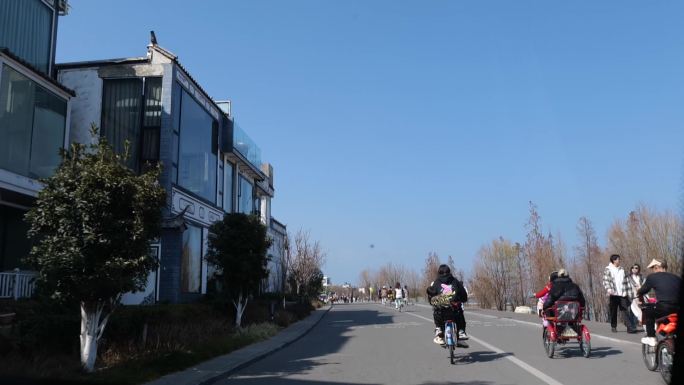 蓝天白云下的景区公园快速穿梭的骑自行车