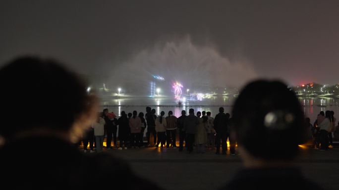 夜晚广场上市民看水幕喷泉