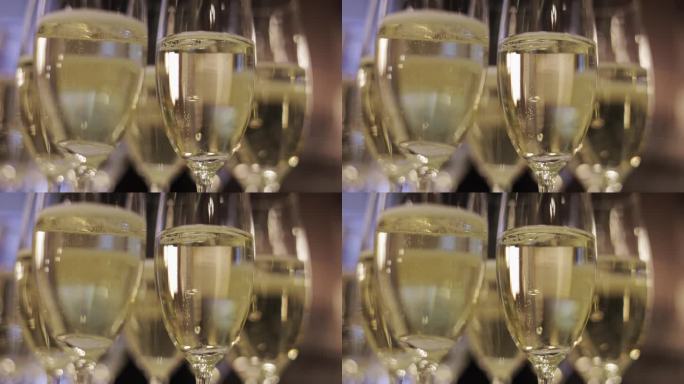多杯香槟酒的特写镜头，上面的气泡表明餐厅里正在庆祝节日。清澈高挑的玻璃杯展现出饮料的金色。酒精和节日