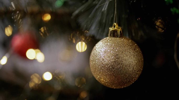 金色闪亮的圣诞球挂在云杉树枝上的背景灯