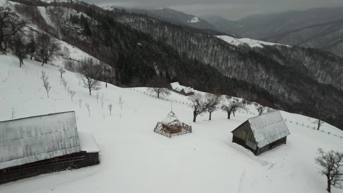 白雪覆盖的山景与传统民居，灰蒙蒙的天空，宁静的冬日景象，鸟瞰