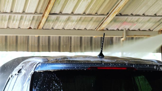 用高压水喷在车顶上粘着去污剂泡沫的地方。