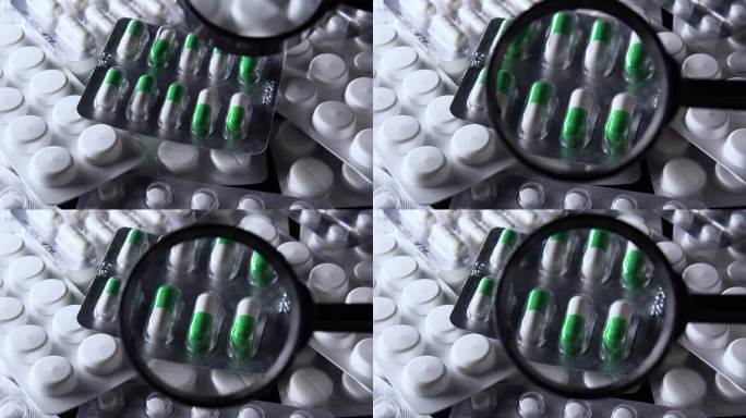 通过放大镜查看白色和绿色胶囊的水泡与其他药片，质量和有效期检查，检查片剂的原创性和符合标准