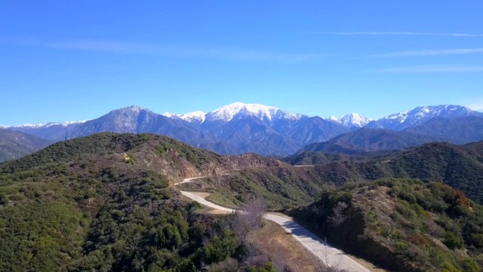 从空中俯瞰一条蜿蜒的山路，通向背景中的雪山。格兰多拉山路。