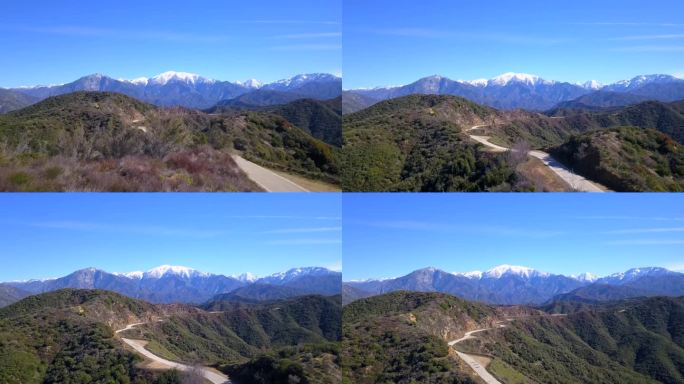 从空中俯瞰一条蜿蜒的山路，通向背景中的雪山。格兰多拉山路。