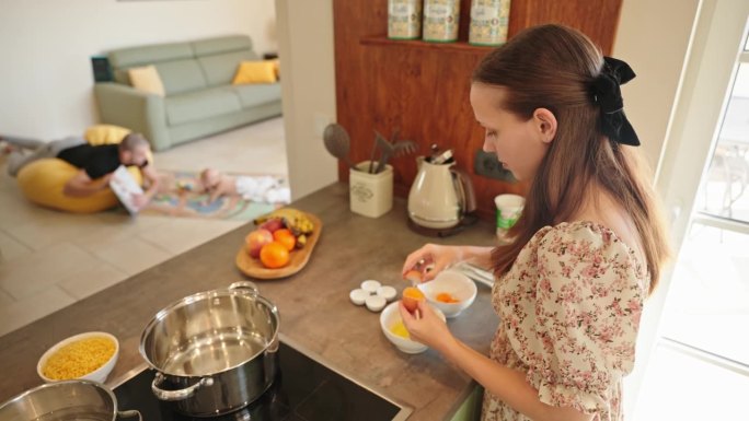 年轻女子在厨房里和家人在客厅里把蛋清和蛋黄分装进碗里
