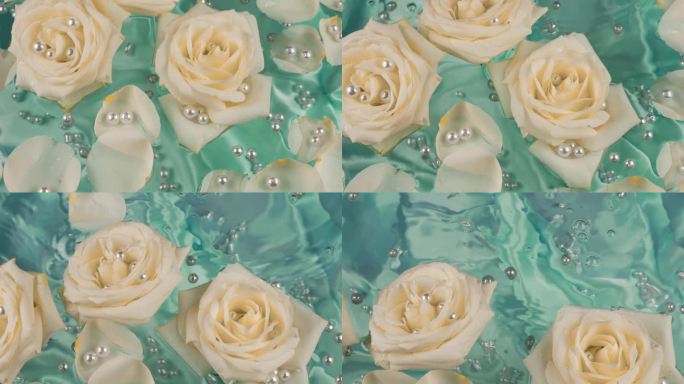 在蓝绿色的丝绸背景上，白色玫瑰的花瓣和珍珠漂浮在水面上。