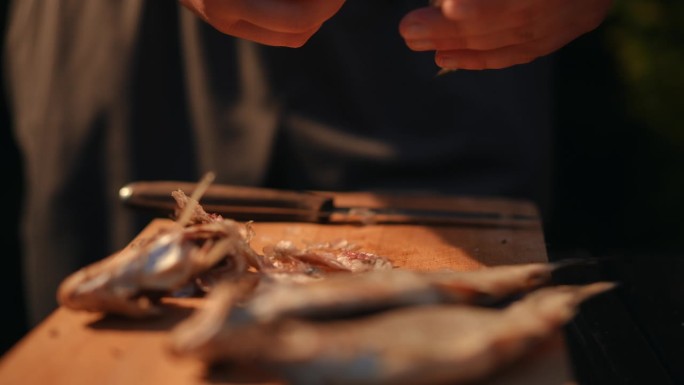 特写镜头。一名男子用手在木板上清洗咸鱼干，然后用菜刀削皮。