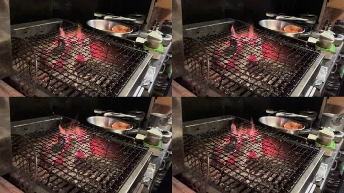 在日本一家餐厅的厨房里，人们正在燃烧网架的炭火。