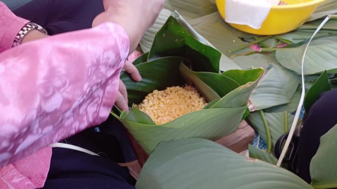手正在包糯米糕，这是越南的传统食品，用猪肉、绿豆、糯米裹上绿叶再煮熟。