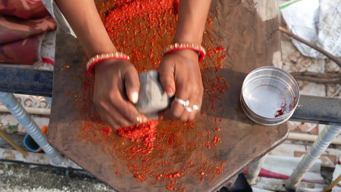 拉贾斯坦邦妇女的手正在用石制的研钵和杵把辣椒磨成传统的印度辣椒酱。