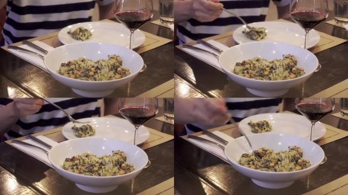 叉子将意大利面从意大利面转到勺子中，菠菜和烟熏鲑鱼盘与红酒一起上桌
