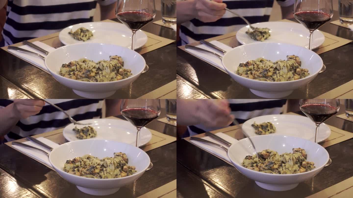 叉子将意大利面从意大利面转到勺子中，菠菜和烟熏鲑鱼盘与红酒一起上桌