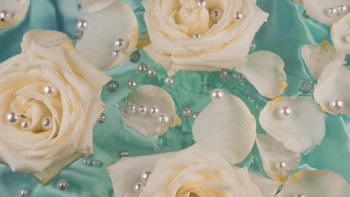 珍珠落在水面上，花瓣和白玫瑰的花朵在绿松石的背景上。
