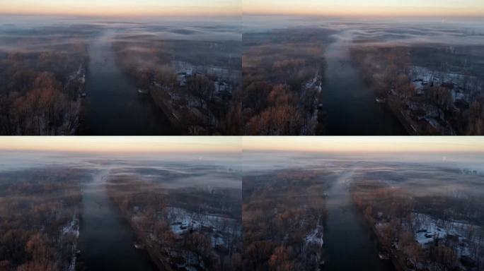 无人机拍摄的雾气在冬天的河流和树梢上移动