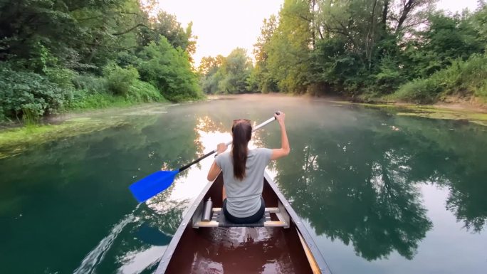 度假的女人，在一条迷人的河上划独木舟