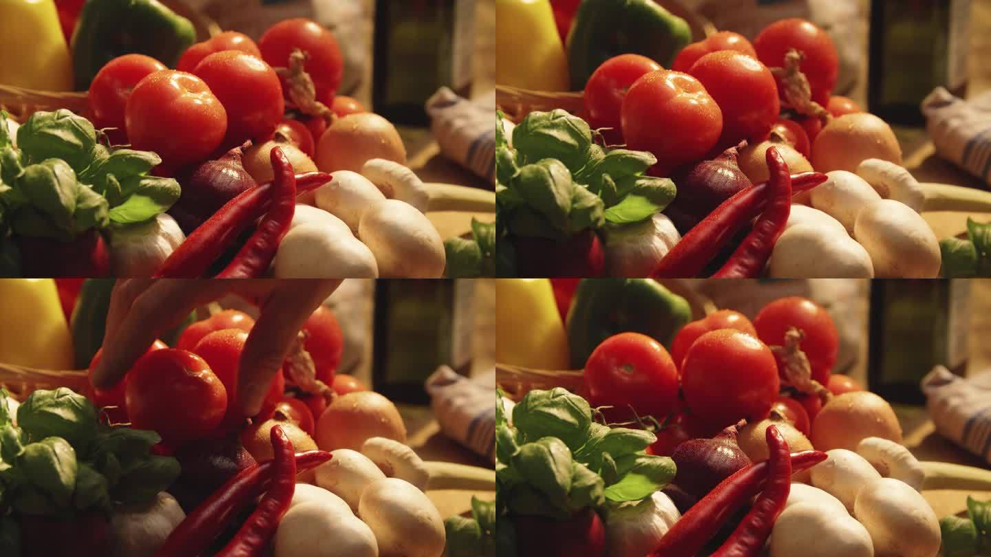 混合蔬菜的特写，手从布景中采摘一个西红柿。用手从菜篮子里拿西红柿的慢动作镜头。