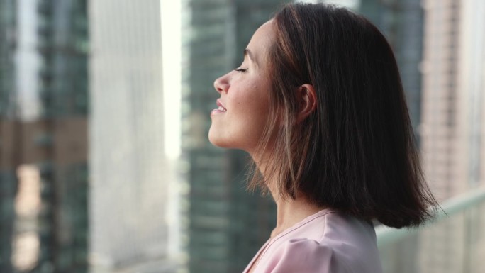 站在阳台上的女人深吸一口气，享受新鲜空气