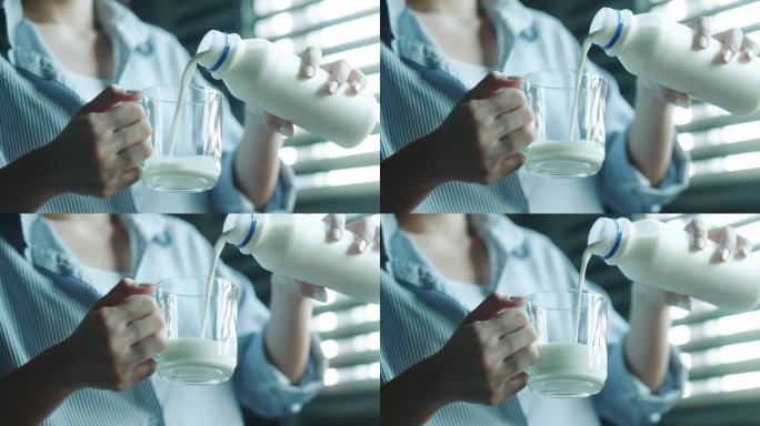 手将牛奶从瓶子倒进玻璃杯的特写镜头