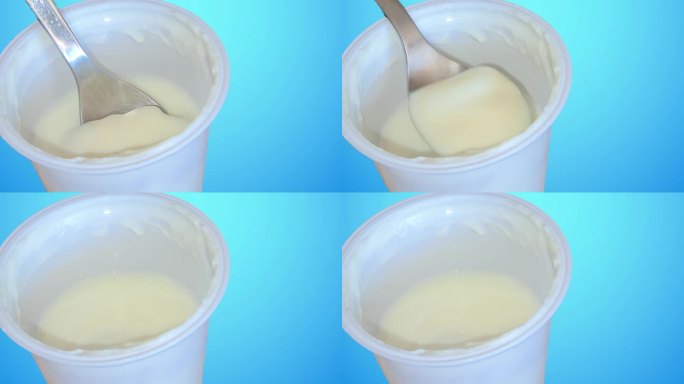 勺子沉入白色酸奶罐，蓝色背景的概念，健康食品和饮食