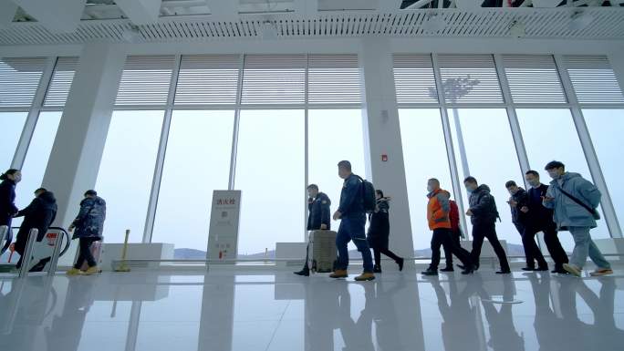 机场大厅一群旅客拖着行李箱行走在航站楼