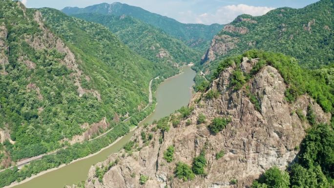 郁郁葱葱的科齐亚山脉与奥尔特河蜿蜒而过，Pietrele Rosiei峰可见，晴天，鸟瞰图