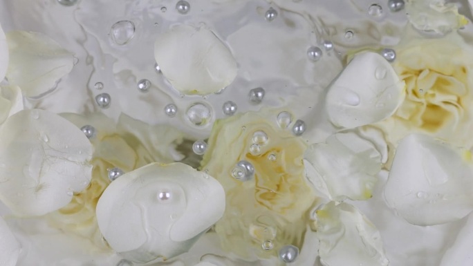 珍珠落在水面上，白色的玫瑰花瓣映衬着水下的玫瑰花。