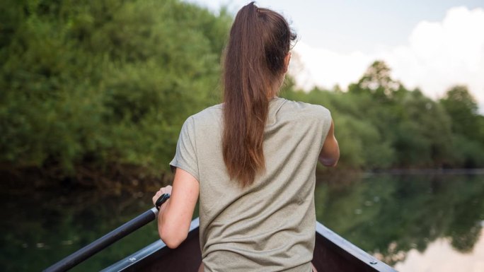 女子在一条令人惊叹的宁静河流上划独木舟