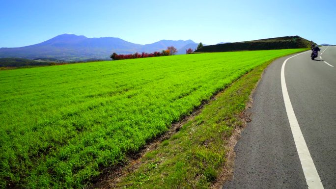 摩托车与浅间山穿过绿色草原:长野县津越村