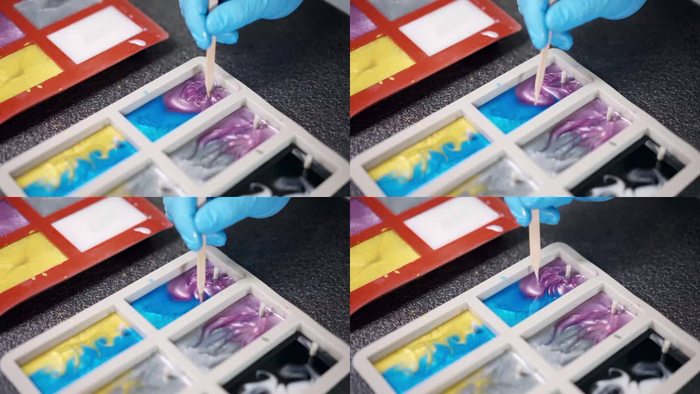 用木棒在硅胶模具上画出环氧树脂的自然图案，在车间混合蓝色和粉色环氧树脂颜料，制作环氧树脂样品用于生产