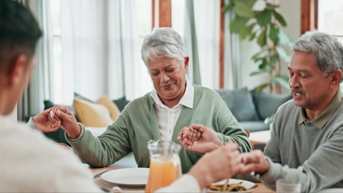 年长的男人，女人和家人在家里的感恩节餐桌上祈祷食物。一群人在敬拜，祈祷或感谢吃午餐，尊重或感谢在餐厅