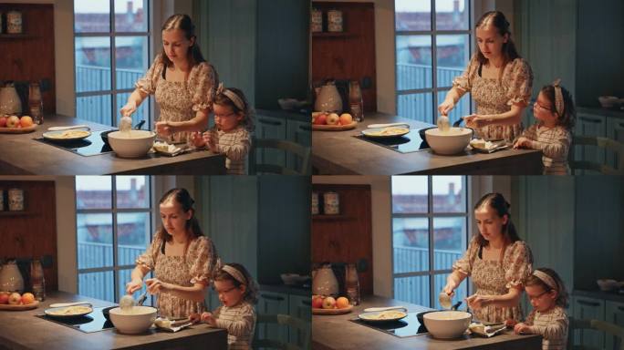 快乐的年轻母亲在家里厨房的女儿旁边用打蛋器在碗里搅拌面液