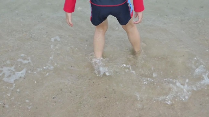 慢镜头，近距离拍摄赤脚孩子在夏日海上旅行的沙滩上快乐玩耍的场景