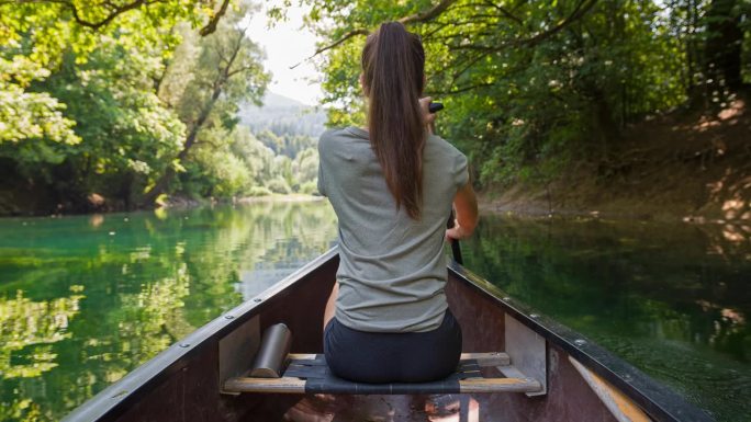 年轻的女旅行者在独木舟上欣赏风景优美的大自然