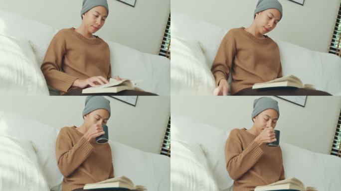 一名年轻的亚洲癌症患者戴着头巾，在阳光明媚、植物丛生的客厅里，坐在舒适的沙发上喝着咖啡，读着书。与癌
