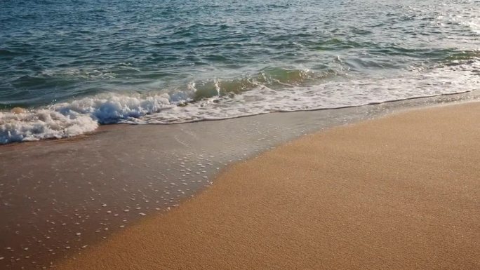 质地移动海浪的海水在金色沙滩岸边夏天的慢动作。海岸。明亮的金色沙子。小浪拍打着沙滩。海洋膨胀。自然