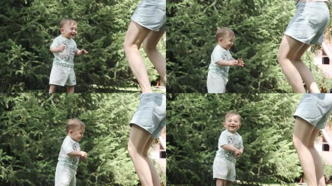 一个穿着t恤和短裤的小男孩在花园的草地上跳舞，旁边是他年轻的妈妈。