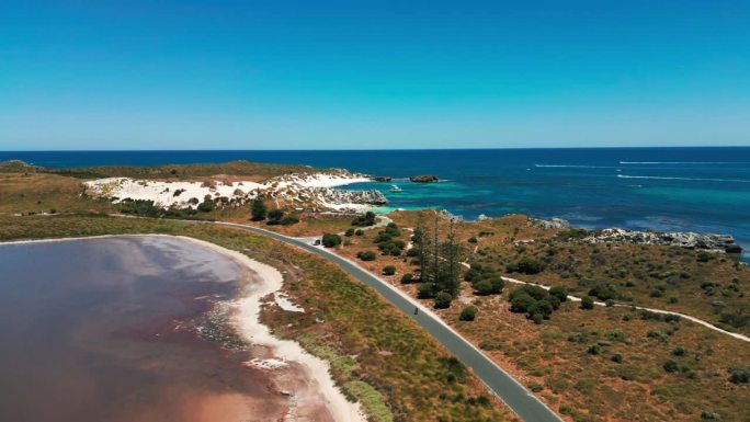 在一个阳光明媚的日子里，西澳大利亚，骑自行车的人在罗特尼斯岛上的海岸公路鸟瞰图