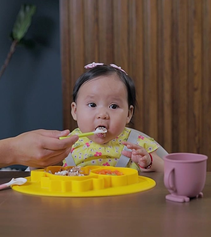 妈妈给宝宝介绍辅食，在家里的餐桌上给他固体食物。婴儿主导的断奶概念